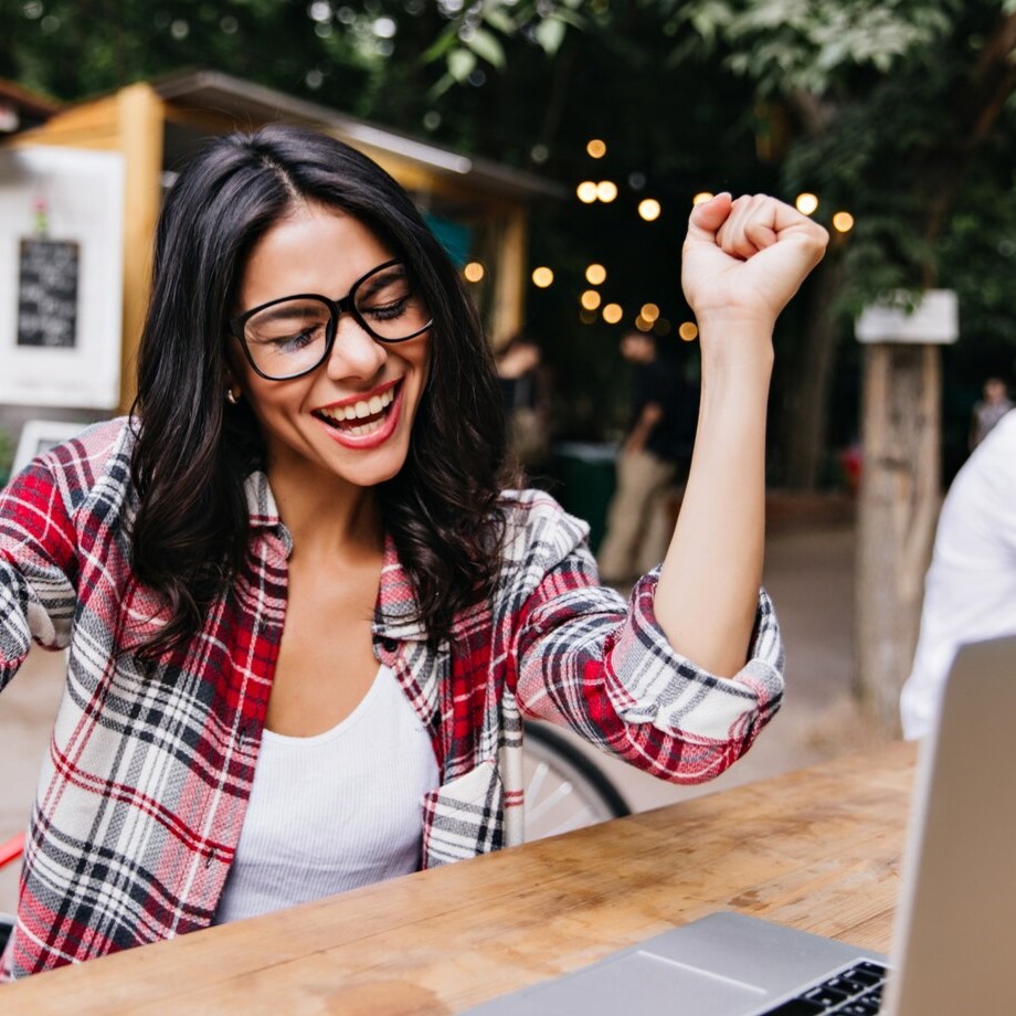 freelancer-feminino-animado-trabalhando-em-um-cafe-ao-ar-livre-retrato-de-menina-morena-emocional-sentada-na-rua-com-o-laptop_197531-19965.jpg